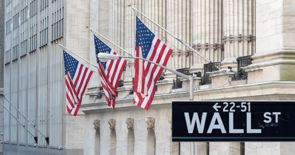 Wall Street sign in view of a large building, highlighting the significance of finance and economic authority in the area.